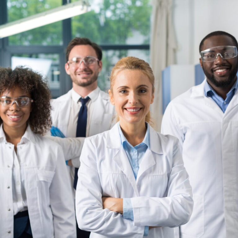 Smiling Group Of Scientists In Modern Laboratory With Female Leader, Mix Race Team Of Scientific Researchers In Lab